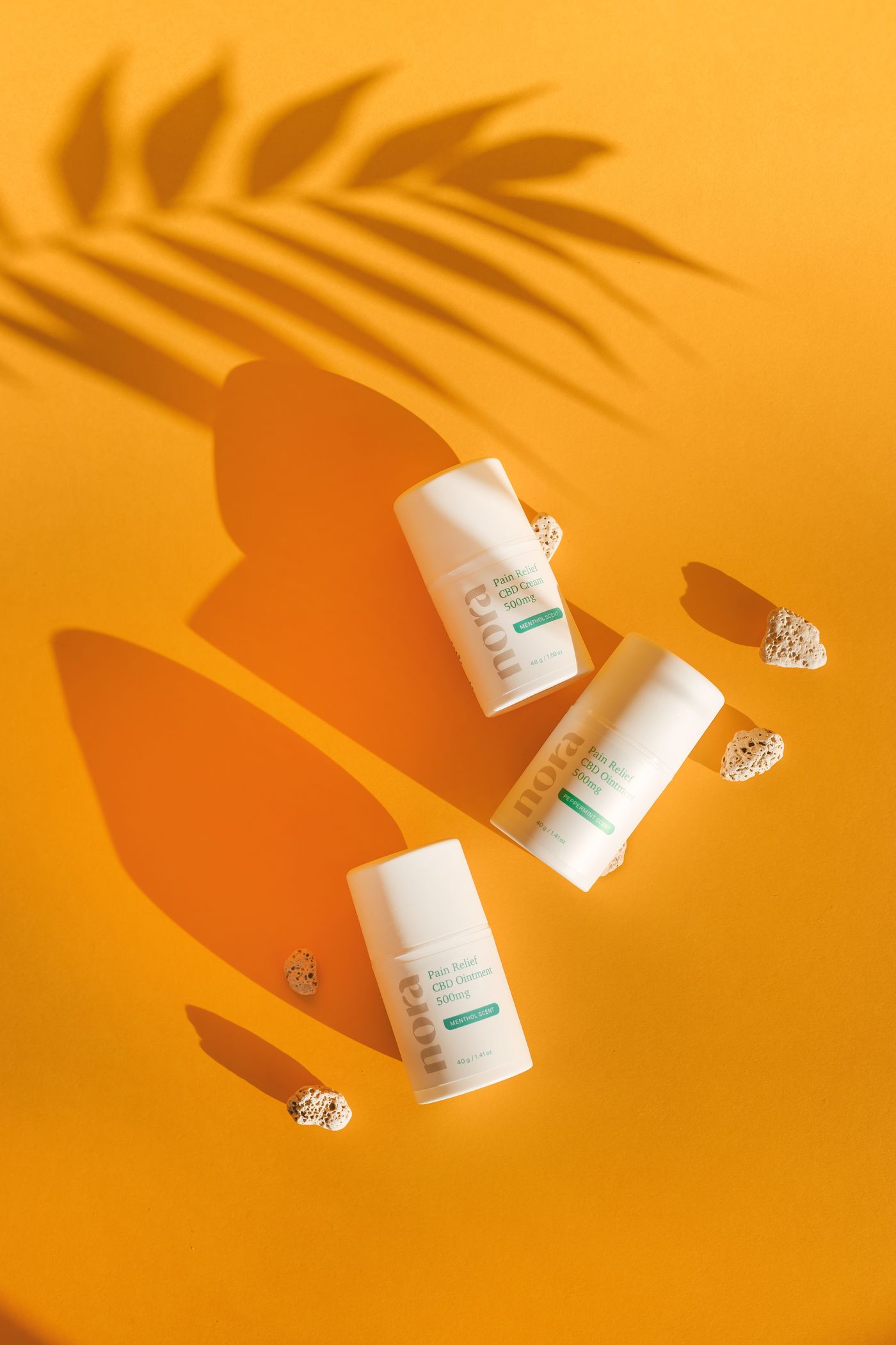Several skincare bottles and jars laid out on a single bright orange surface, each casting a soft directional shadow
