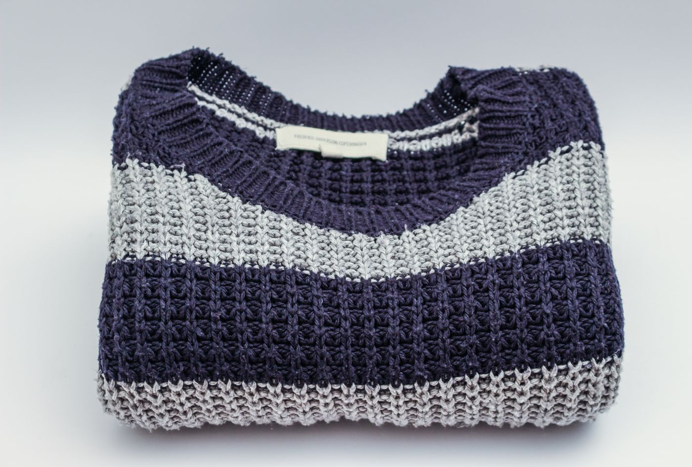 Overhead flat lay of a neatly styled knit sweater arranged on a clean, plain surface