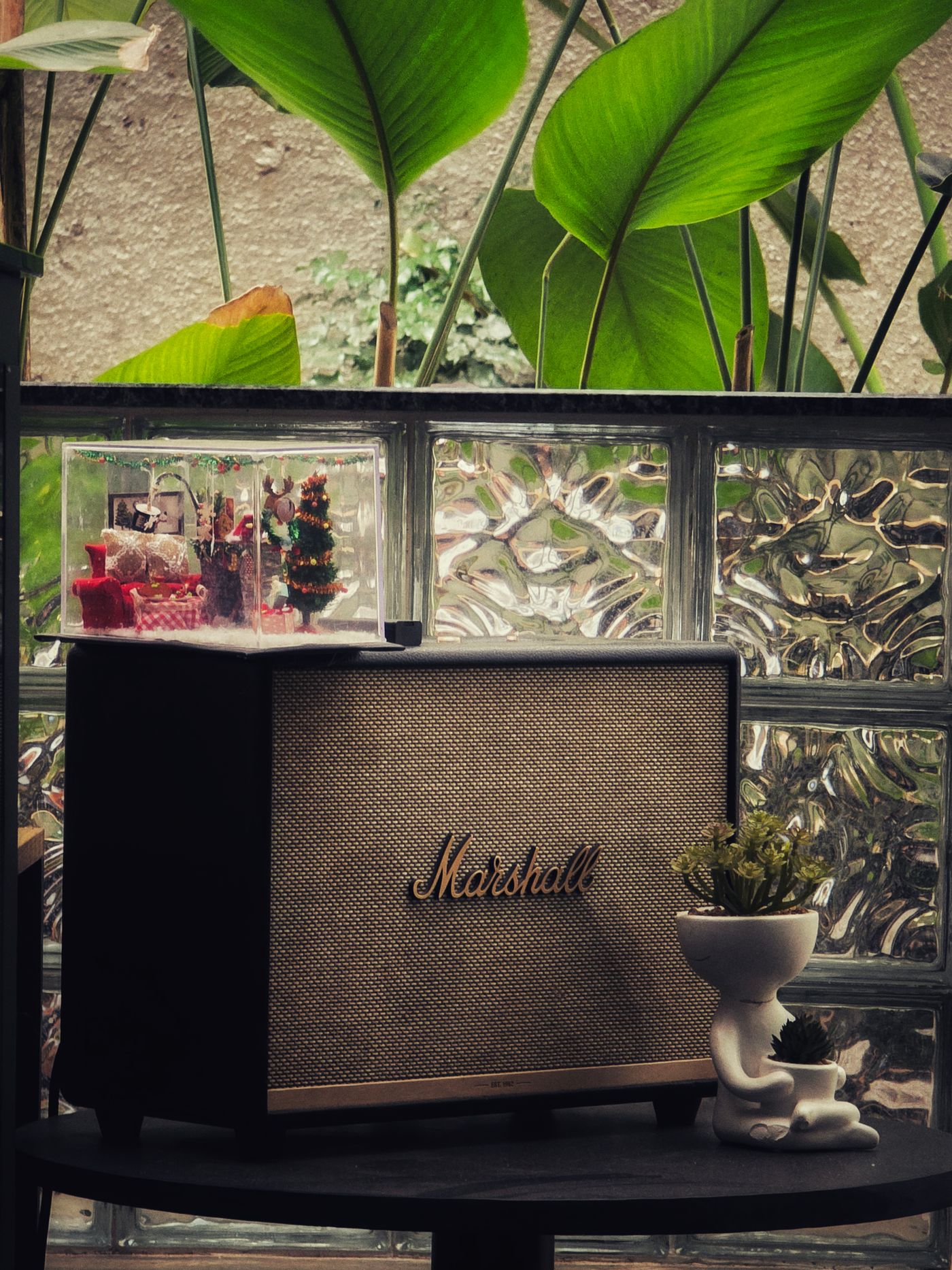 The same wireless speaker shown twice, once as a clean white-background listing photo and once on a festive backdrop surrounded by wrapped gifts