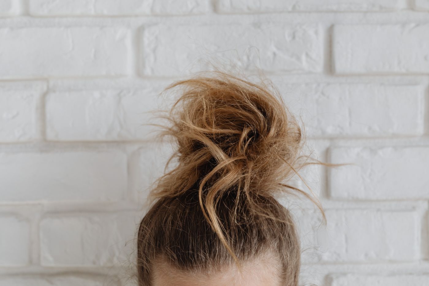 Close-up of loose flyaway hair strands catching light against a plain wall, showing how fine and semi-transparent the edges of hair really are