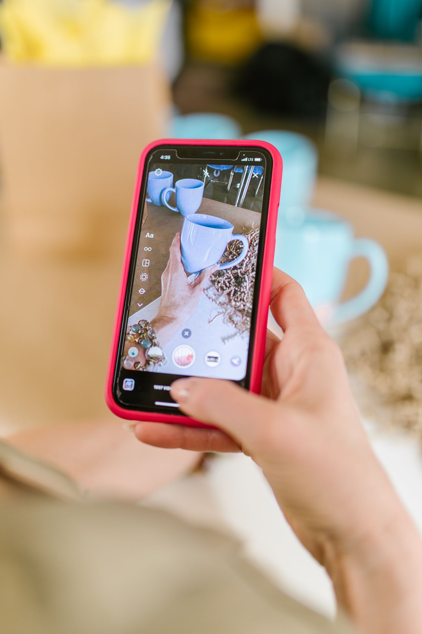 A seller photographing a ceramic mug with a smartphone on a simple tabletop setup beside a bright window