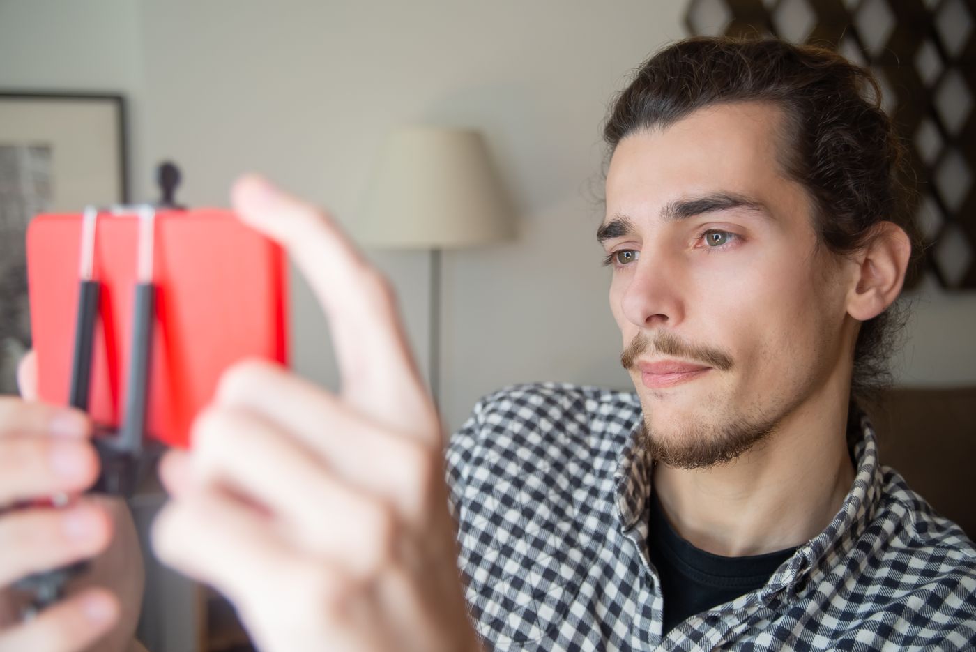 A person taking a resume headshot at home with a smartphone on a tripod facing a window for soft natural light.