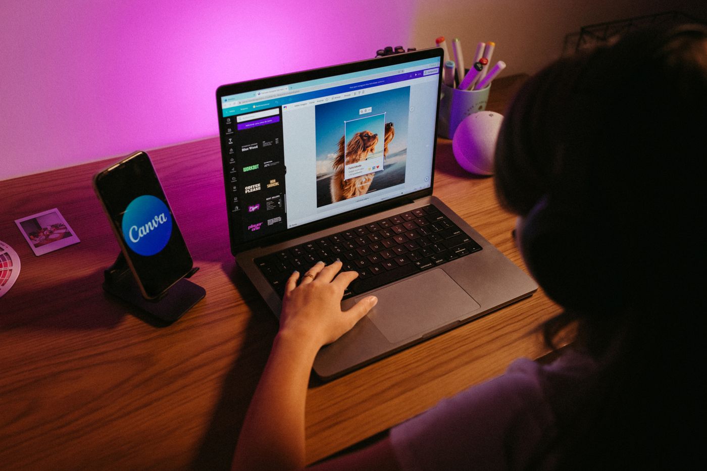 O persoană la birou lucrează pe laptop într-un editor de design, cu o postare de social media în format portret pe canvas