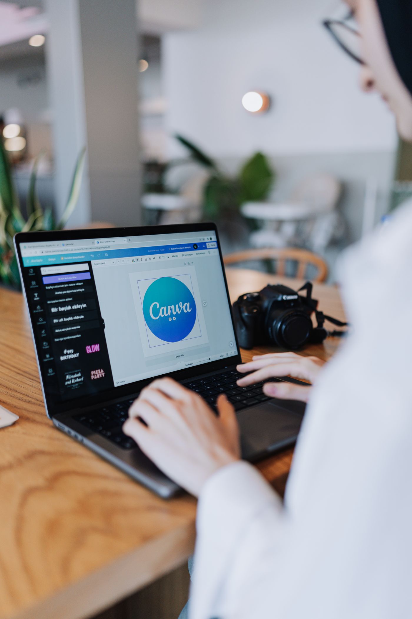 A designer working at a laptop arranging colorful mobile app marketing graphics, smartphone on the desk beside the keyboard