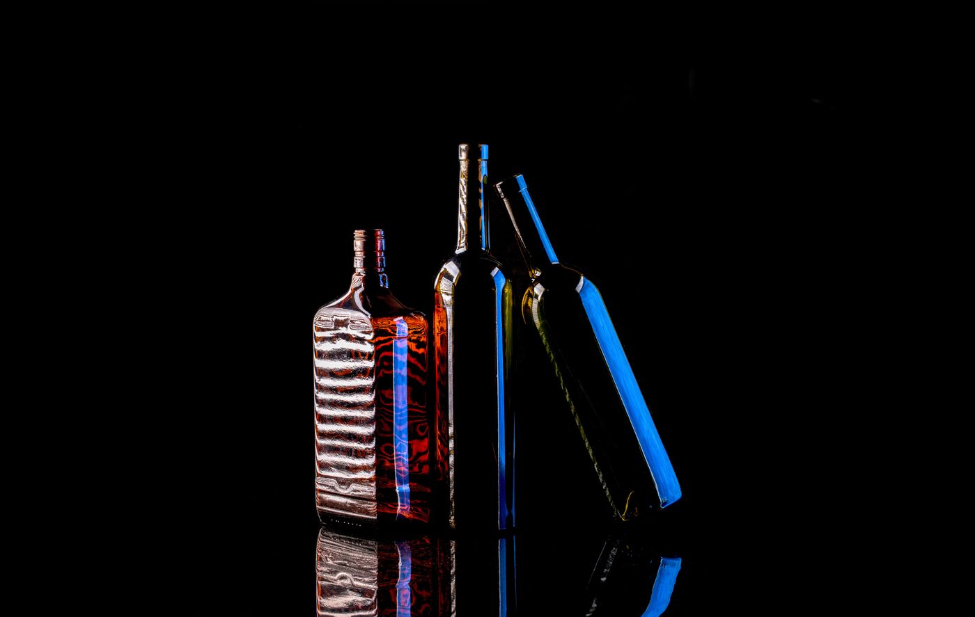 Glass bottle backlit through a diffusion panel, showing glowing edges against a dark backdrop