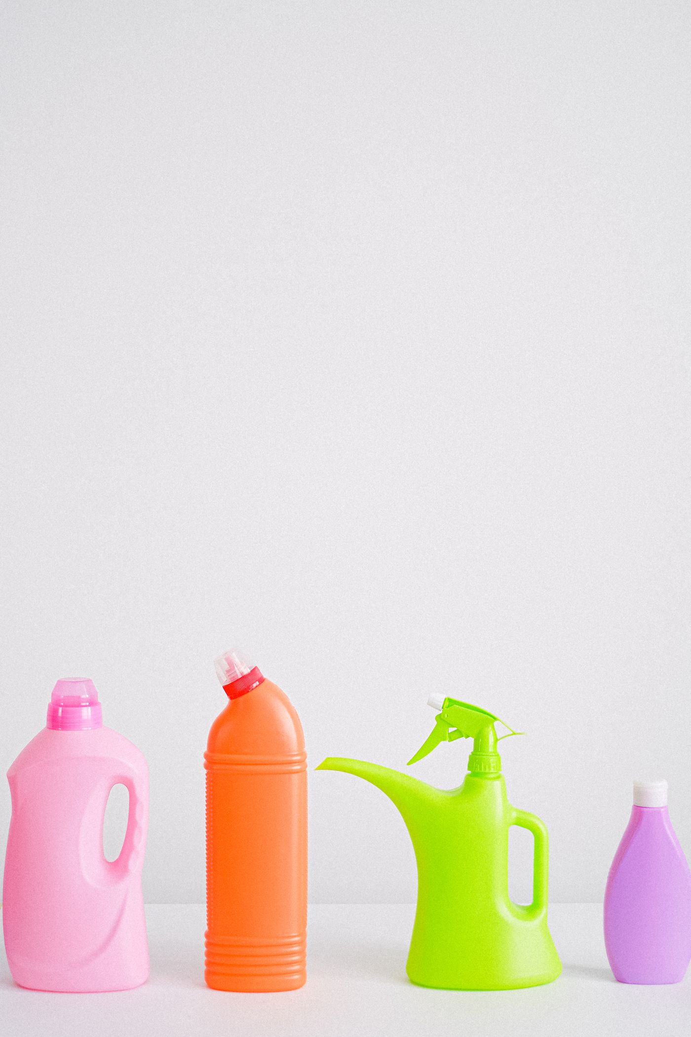 Four plastic bottles of noticeably different heights and shapes standing in a row against one plain white backdrop