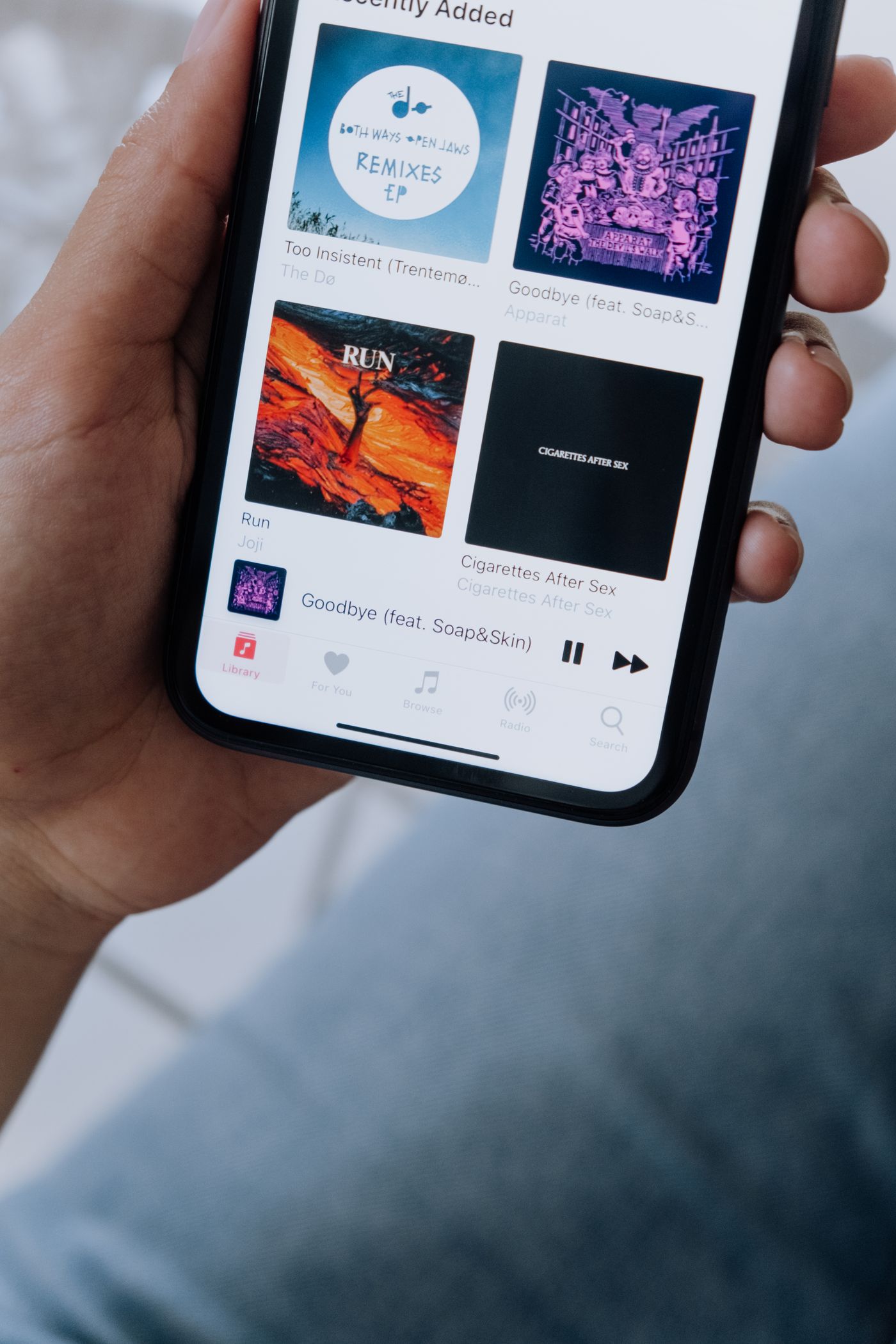 Küçük kare program kapaklarından oluşan bir podcast uygulaması grid'ini gösteren akıllı telefon