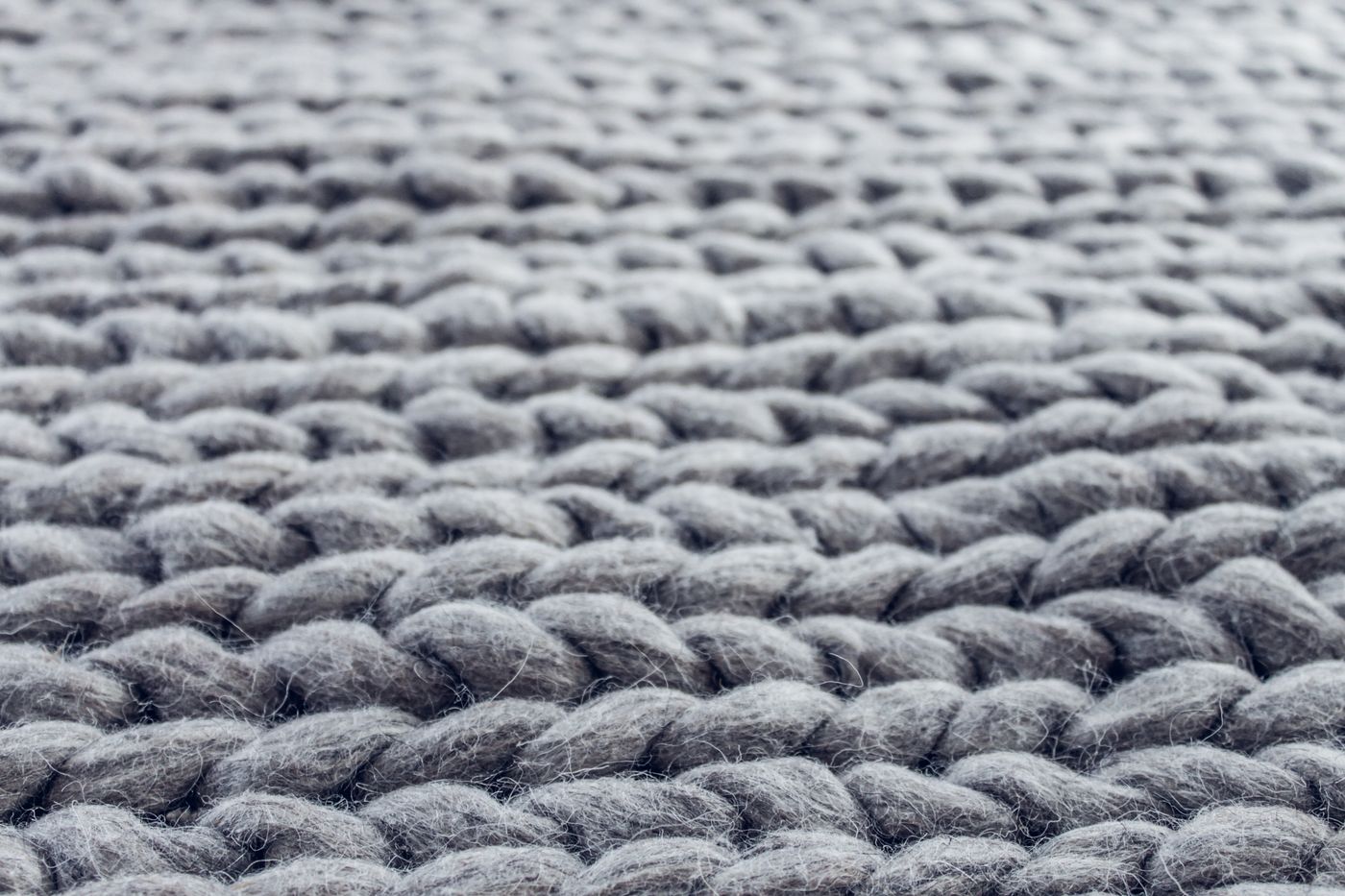Extreme close-up of chunky grey cable-knit wool, with individual fibres and stray strands visible along each stitch