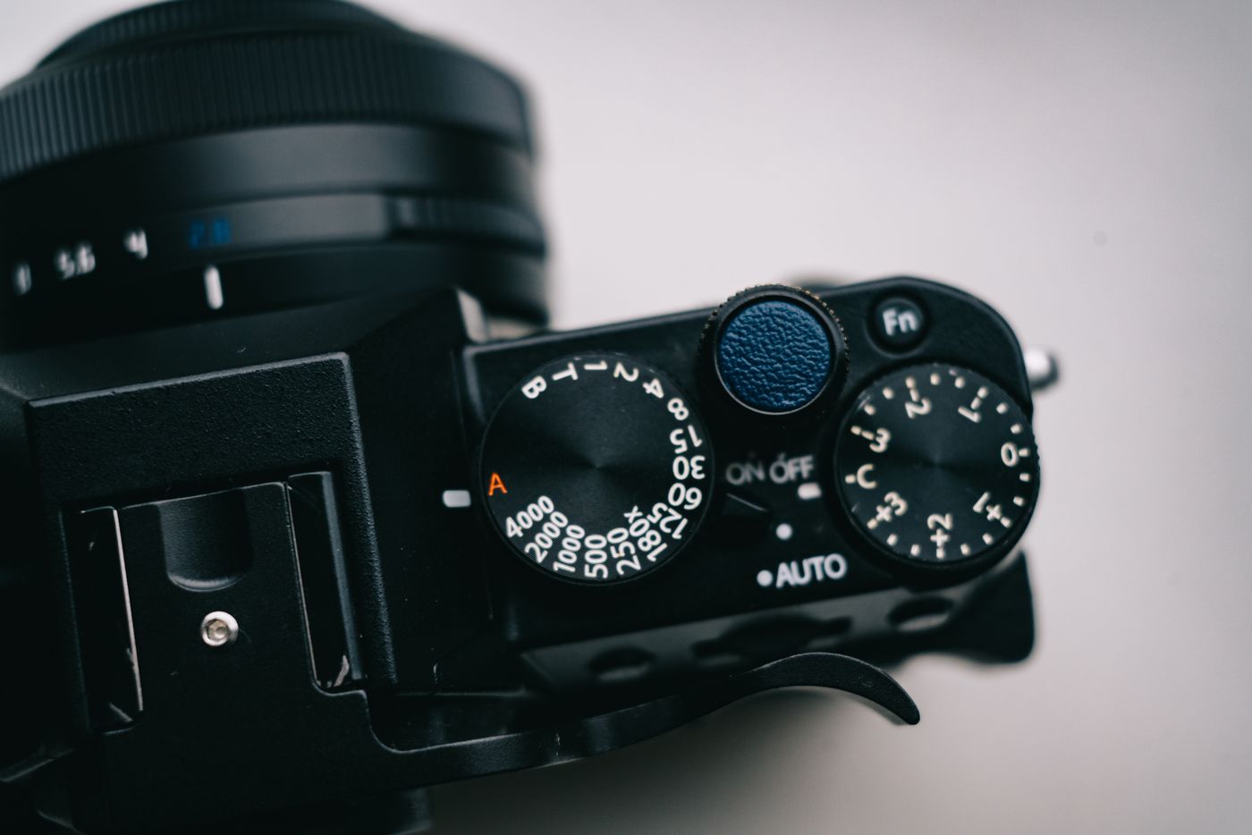 Close-up of the top plate of a black mirrorless camera showing a shutter-speed dial marked 4000 down to 1, next to an exposure-compensation dial and the ON/OFF switch.